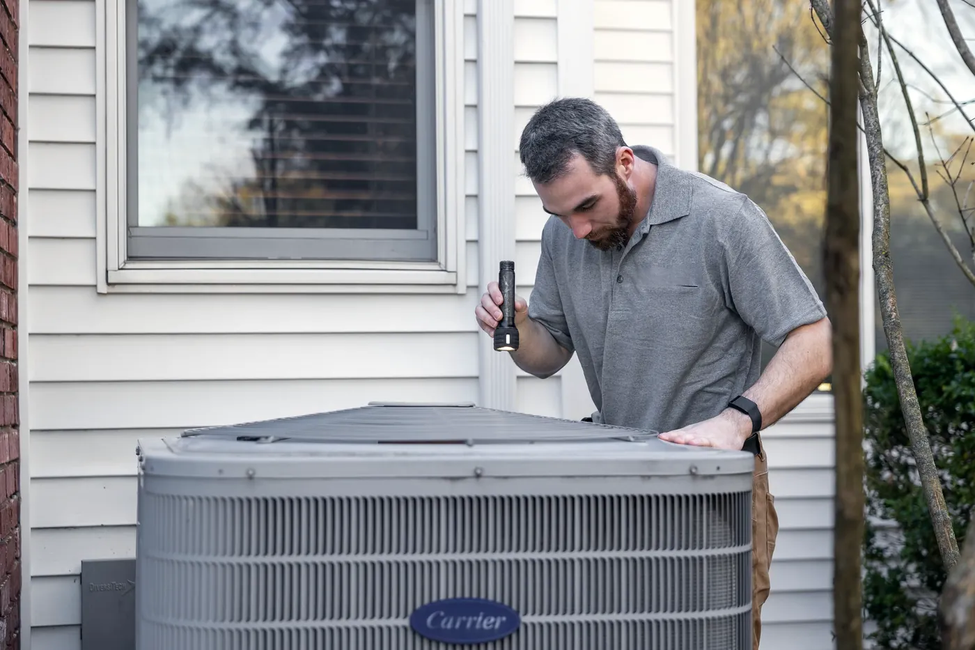 HVAC technician servicing a residential AC condenser beside a Florida home
